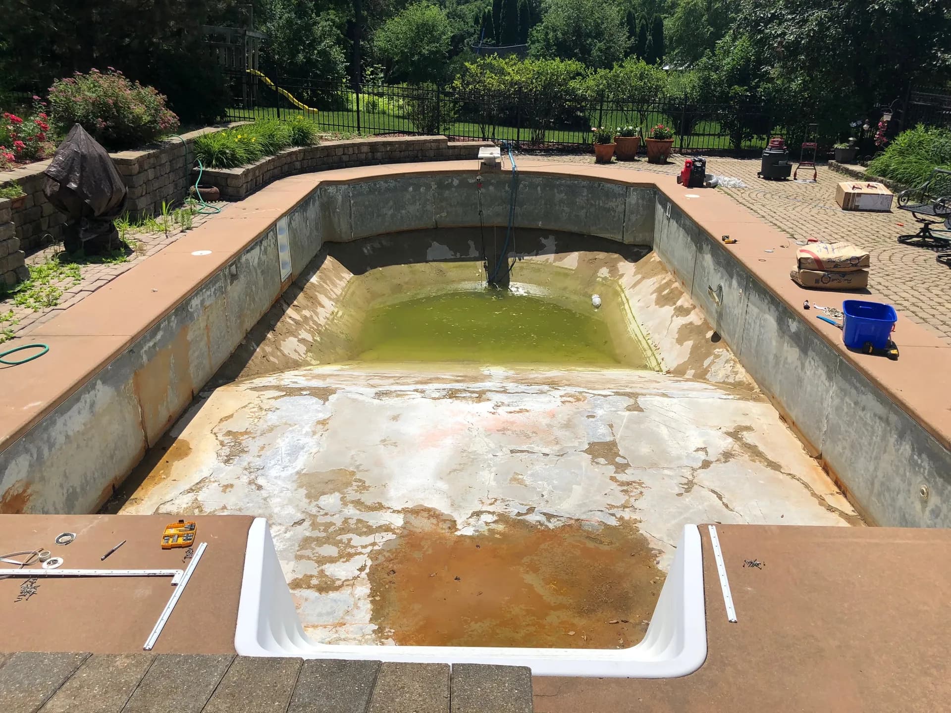 Drained inground pool with the old vinyl liner removed, exposing the stained floor and wall panels