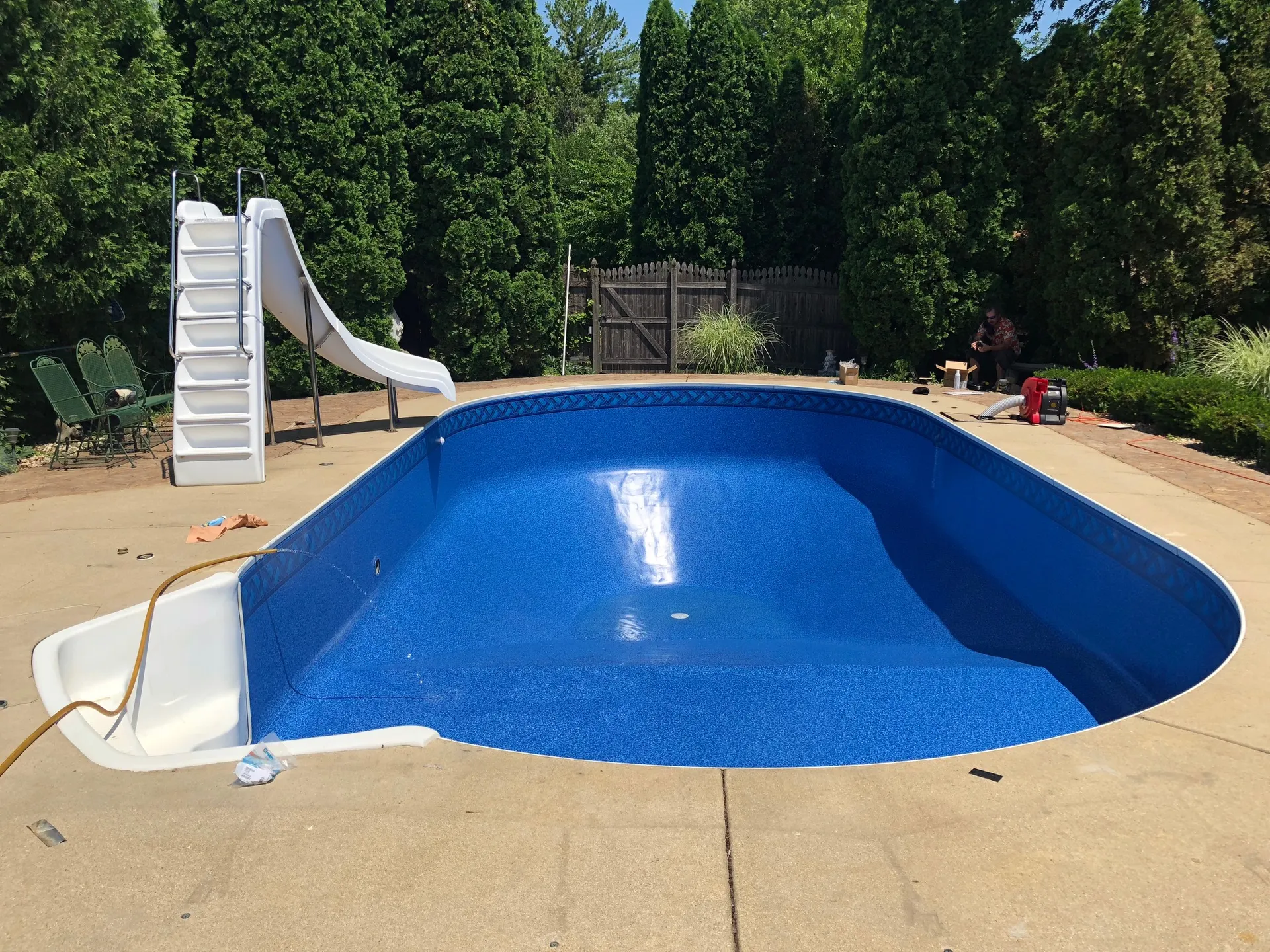 The same pool after renovation with a new blue vinyl liner, refinished steps and slide back in place